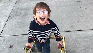 Rachelle Chase's son in a striped sweater and glasses with a device helping him walk