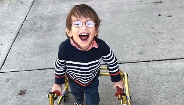 Rachelle Chase's son in a striped sweater and glasses with a device helping him walk