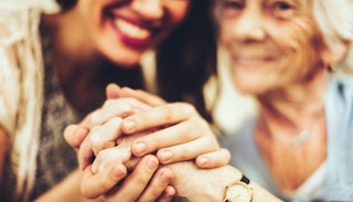 Daughter happily holding hands with her mother who has Alzheimer's