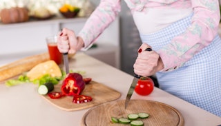 A mom angrily cutting the veggies in the kitchen with two knives because she is sick of eating healt...