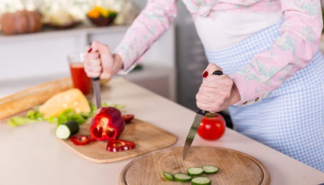 A mom angrily cutting the veggies in the kitchen with two knives because she is sick of eating healt...