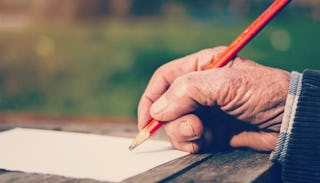 Close up of a grandpa who was a sexual predator holding a pencil with a clear sheet of paper in fron...