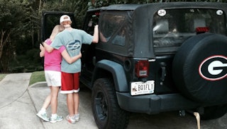 Parent hugging her child next to a Jeep.