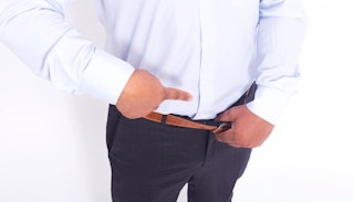 A man wearing a blue shirt and pants encouraging men to get a vasectomy by pointing to his crotch