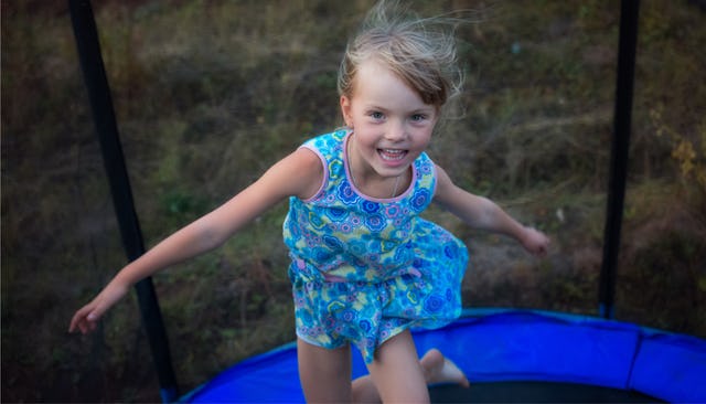 Despite the risks of trampolines, a little girl jumping on one