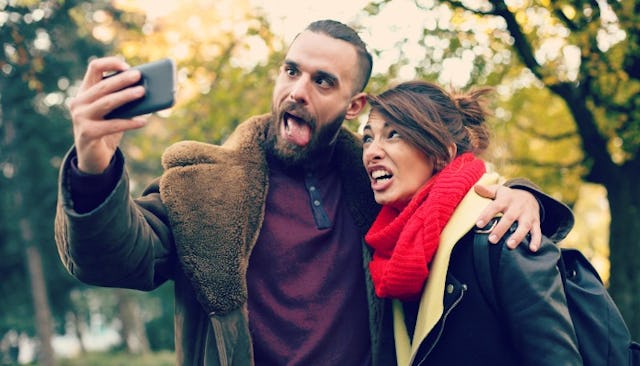 Guy wearing a brown coat and a woman wearing a black jacket taking a selfie with silly faces