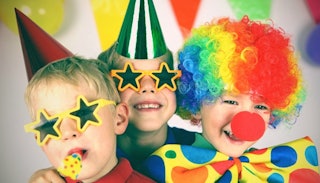 Three kids dressed in multi-colored clown party costumes