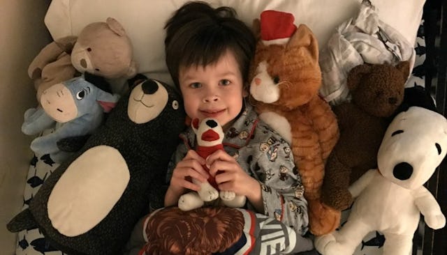 Child laying in bed surrounded by toys 