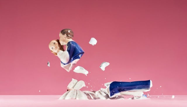 A broken ceramic figure of a just married couple wearing a blue suit and white dress representing di...
