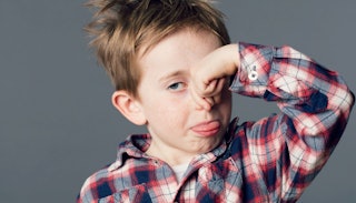 A child in a checkered shirt holding his nose