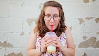 Woman drinking a lemonade which she is holding with both hands, not caring about her weight anymore 