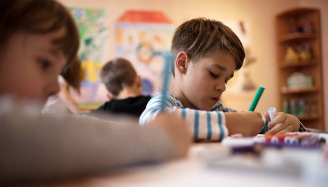 A young boy in kindergarten class writing something down