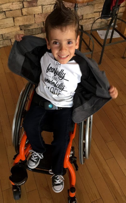 A little happy boy sitting in a wheelchair in a white shirt, black jacket and black pants