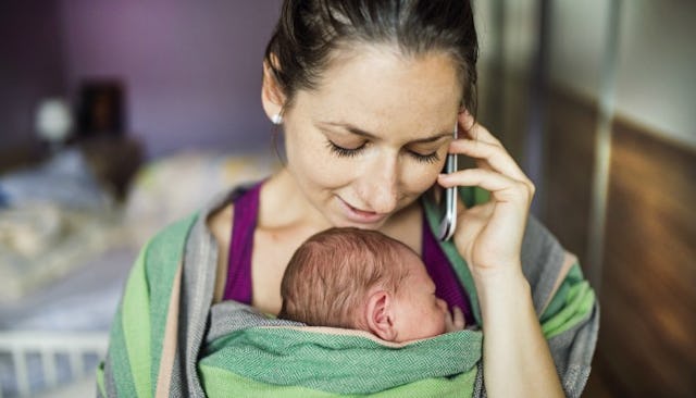 Mother cuddling her velcro baby while talking on the phone