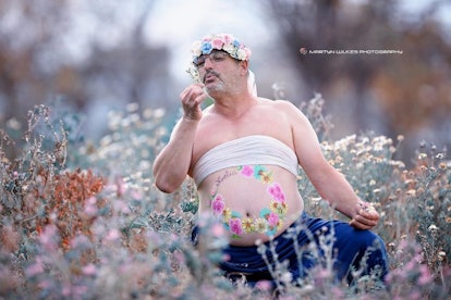 Dad's maternity photo with him sitting in a field of wildflowers