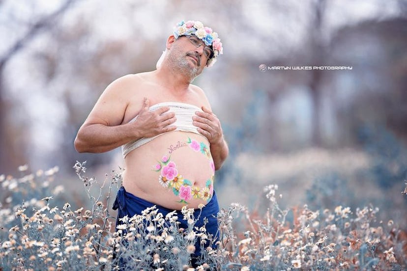Dad's maternity photo with him cupping his breasts in a field of wildflowers