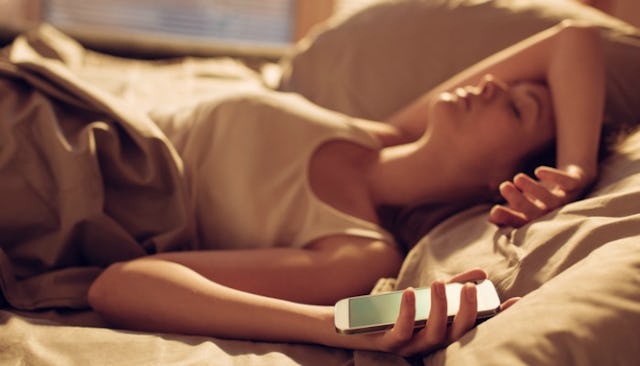 A woman with mental illness sleeping in her bed while holding her phone in her left hand