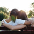Two reconciled girls sitting hugged on a bench