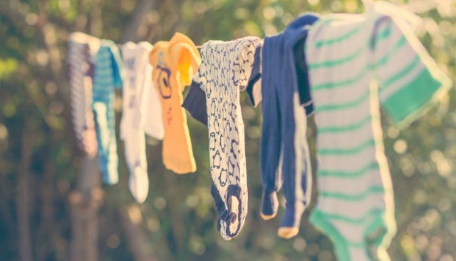 Hand-me-down baby clothes drying outside on a wire 