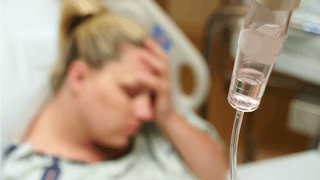 Tired woman laying in the hospital while getting the infusion after experiencing hysterectomy
