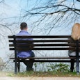 A man and a woman separately sitting on a bench 