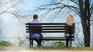 A man and a woman separately sitting on a bench 