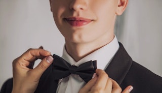 Close up of a young man getting his bowtie fixed from prom
