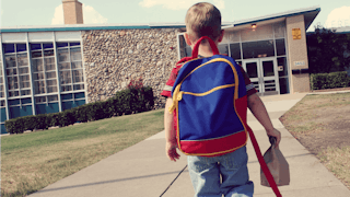 5-year-old kid carrying a backpack on his way to the kindergarten