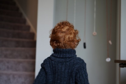 A red haired boy walking through the house.