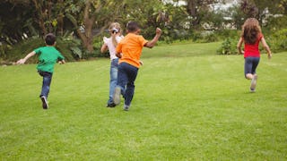 Two boys and two girls running across a grass field in an U.S. School