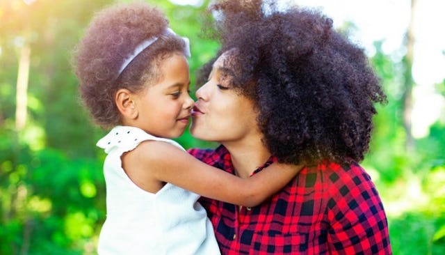 A single mother kissing her daughter's cheek