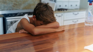 An exhausted tween kid, laying face down on a kitchen table