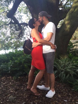 A couple kissing in front of a tree