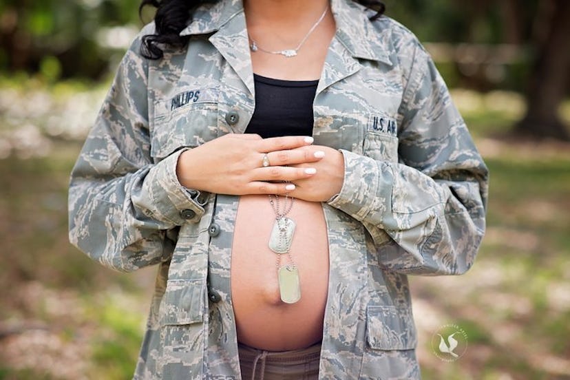 A pregnant wife wearing her husband’s army jacket and holding his two necklaces 