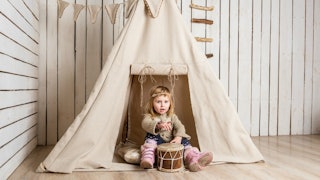A child playing in front of a tent made indoors 
