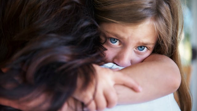 The back of a dark-haired woman and her brunette blue-eyed daughter with special needs looking over ...