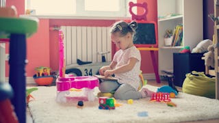 A little girl playing with toys in a messy room 