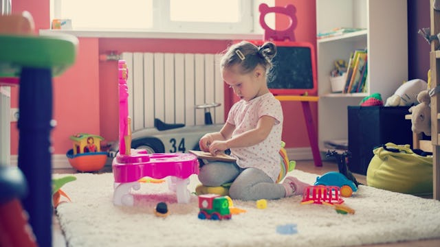 A little girl playing with toys in a messy room