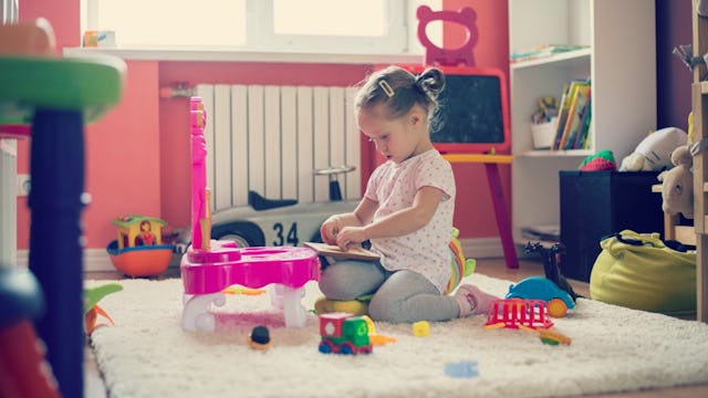 A little girl playing with toys in a messy room 