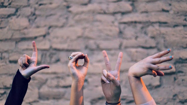 Four hands spelling out the word LOVE, each showing one letter