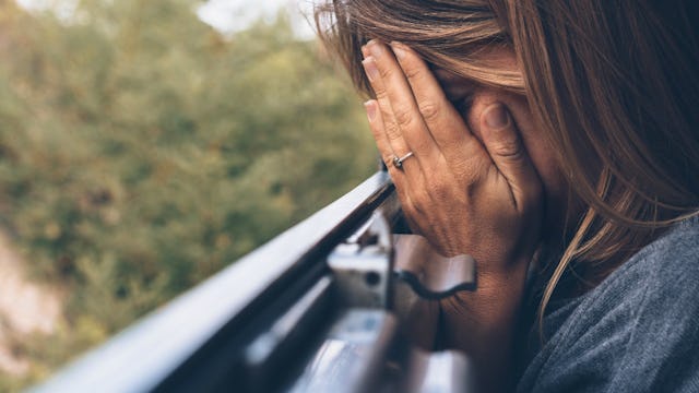 A mom living with a mental illness covering her face with her hands