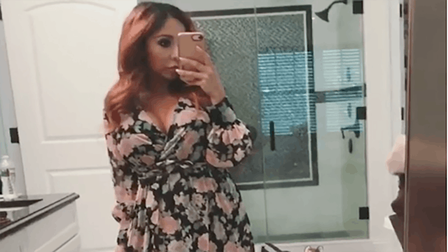 A screenshot from an Instagram video post by Snooki in a floral dress in a mirror reflection