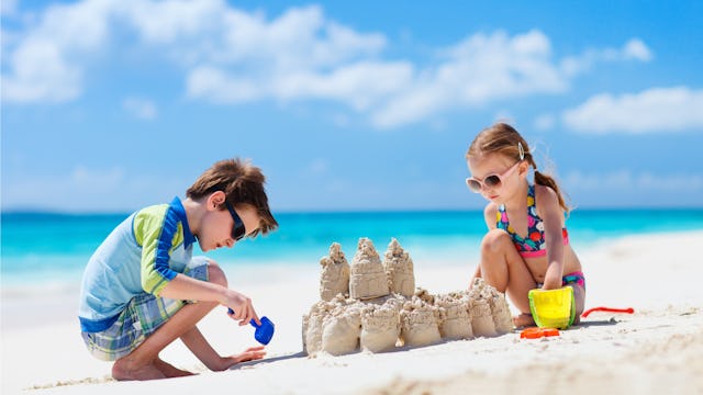 Two toddlers making a sandcastle on a beach 