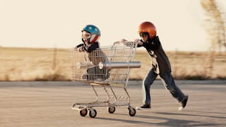 Two boys with ADHD playing and running with a shopping cart and helmets on their heads