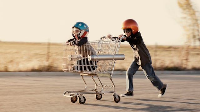 Two boys with ADHD playing and running with a shopping cart and helmets on their heads