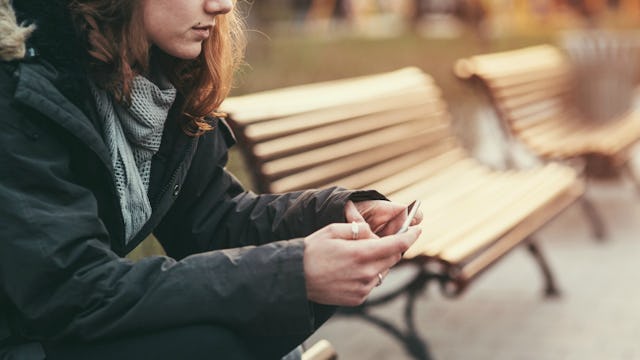 A woman dressed in a black jacket is sitting on the bench