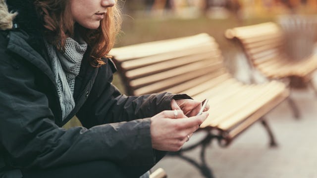 A woman dressed in a black jacket is sitting on the bench 