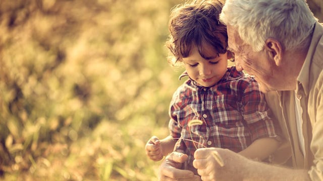 A grandparent hugging and talking to his grandson in a park