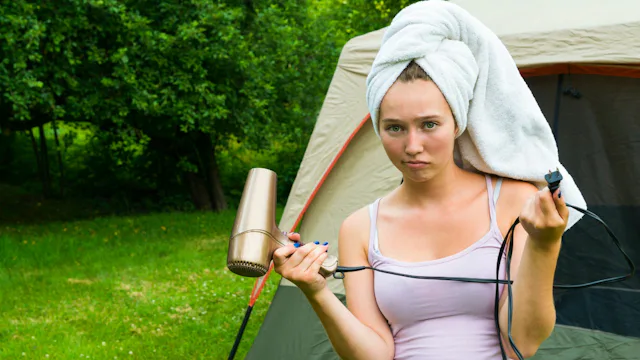 Furious woman standing in front of a tent on camping with a towel on her head