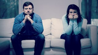 A man and a woman sitting on the couch after a fight